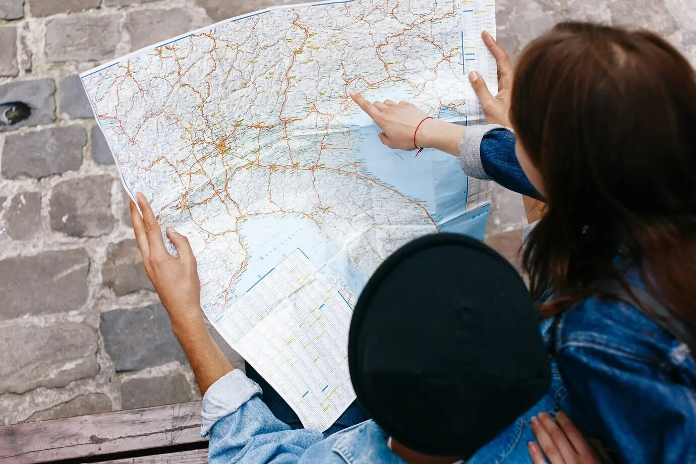 Мужчина и женщина сидят на скамейке и смотрят на карту где-то в старом городе.